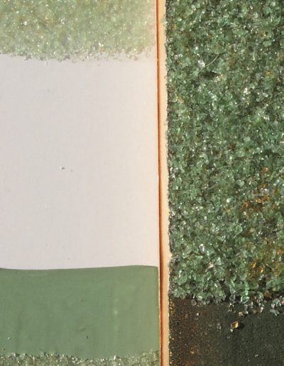 7-Recherche de grosseur des grains de verre et de la couleur de fond : à droite, gros grains et fond vert foncé ; à gauche en haut grains fins sur fond blanc et en bas, grains fins sur fond vert clair. Quelques grains de verre brun sont mélangés au verre vert.